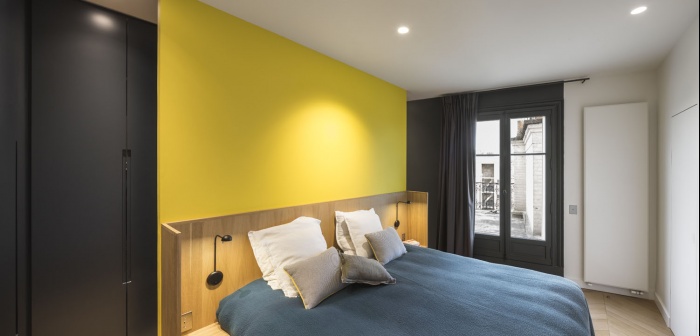 Boulainvillers : Dans la chambre des parents, la tte de lit en chne est adosse contre un mur jaune tournesol. Couleur qui se retrouve  lintrieur des placards sur mesure, aux poignes en creux.
